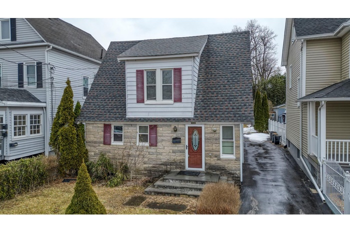 View of front facade with stone siding and roof with shingles