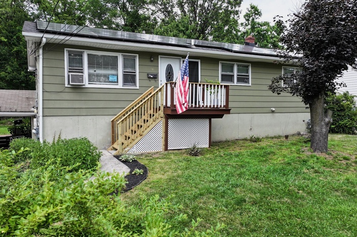 View of front of property featuring a front lawn and roof mounted solar panels