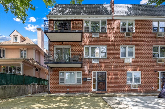 View of front of house featuring a balcony and brick siding