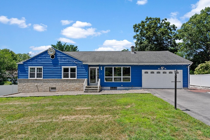 Ranch-style house featuring roof with shingles, entry steps, an attached garage, and driveway