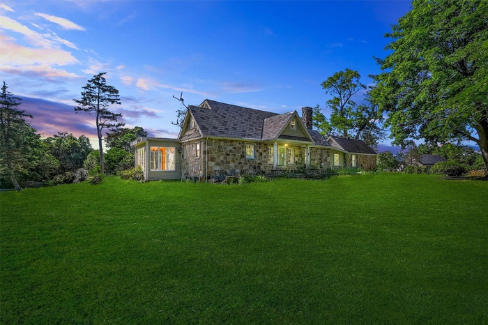 View of home's exterior featuring a chimney, a yard, and stone siding