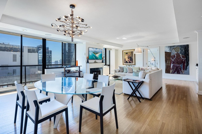 Dining area with an inviting chandelier, wood finished floors, baseboards, and a glass covered fireplace