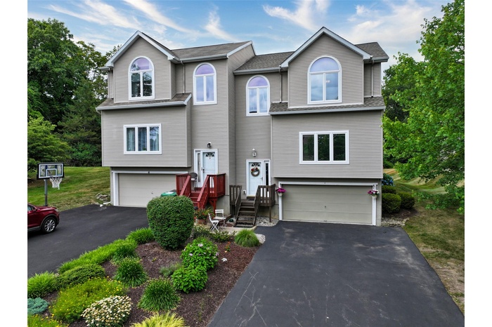 View of front of property featuring a garage, driveway, and a shingled roof