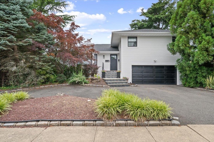 View of front of home featuring asphalt driveway, an attached garage, and a shingled roof