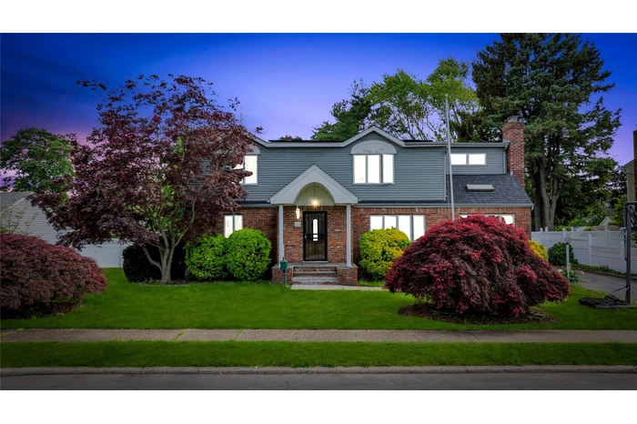 View of front of home featuring a chimney and brick siding