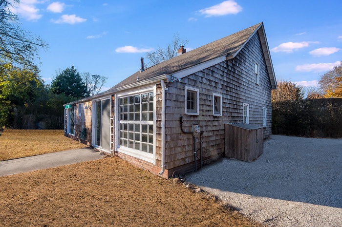 View of home's exterior with a chimney, roof with shingles, and a lawn