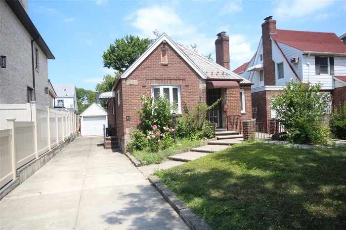 View of front of house with an outbuilding, brick siding, and a detached garage