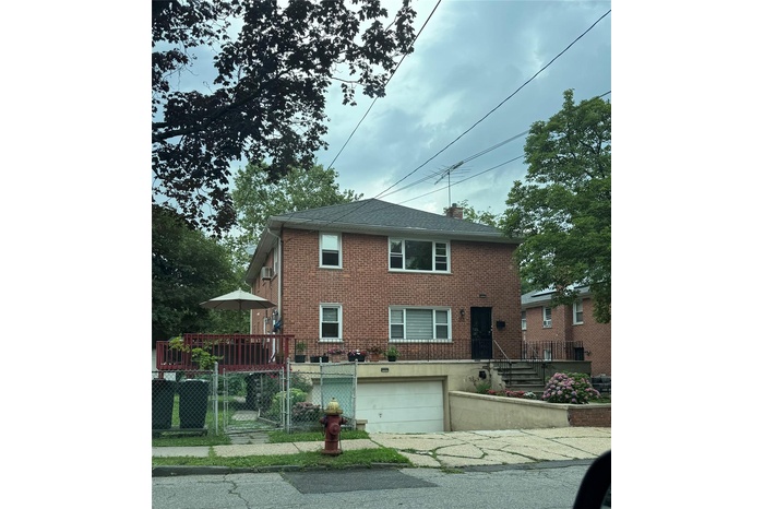View of front facade featuring a garage, brick siding, a fenced front yard, a chimney, and concrete driveway