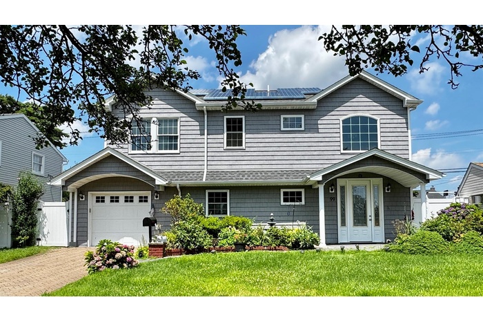 View of front of property with solar panels, a front yard, a garage, and driveway