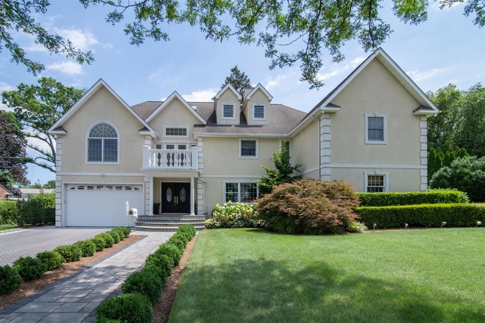 Traditional-style home featuring stucco siding, a garage, a front yard, driveway, and a shingled roof