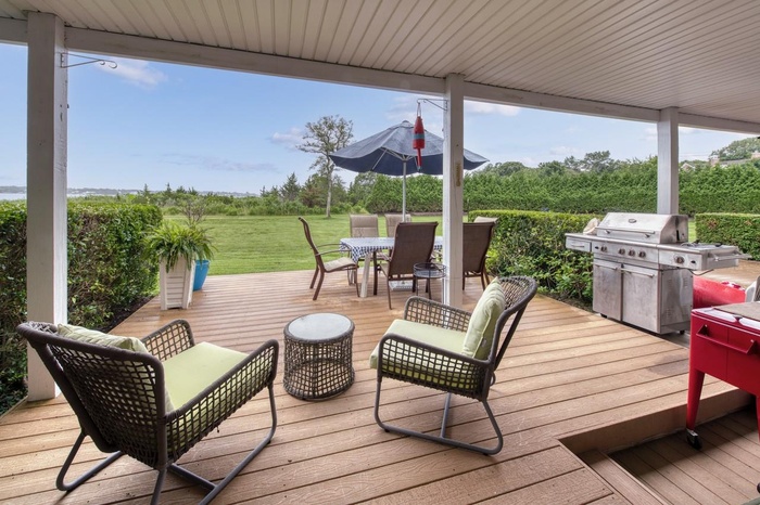 Wooden terrace with outdoor dining space, a grill, and a lawn