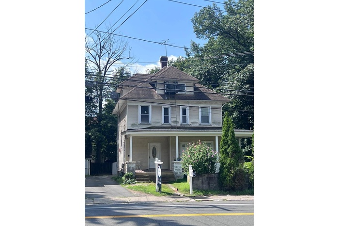 American foursquare style home featuring a porch and a chimney