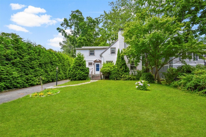 View of front of property featuring a front lawn, a chimney, and driveway.