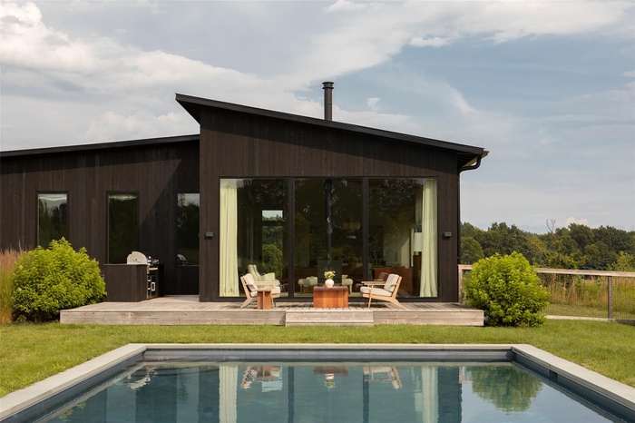 Back of house with a wooden deck, an outdoor pool, and a lawn