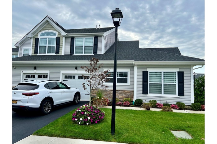 View of front of home featuring a front yard, driveway, an attached garage, and a shingled roof