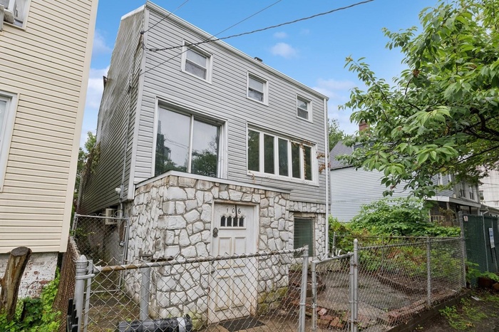 Rear view of property with stone siding and a gate