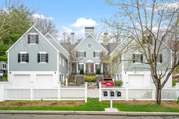 Shingle-style home featuring a chimney, a garage, and a fenced front yard