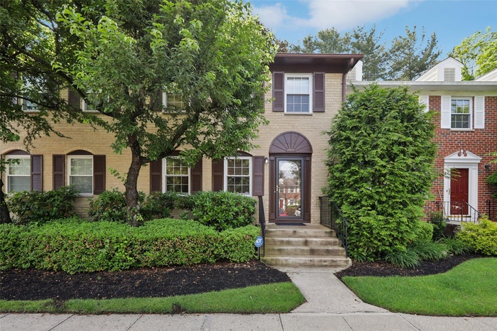 Front door view surrounded by lush mature landscaping.