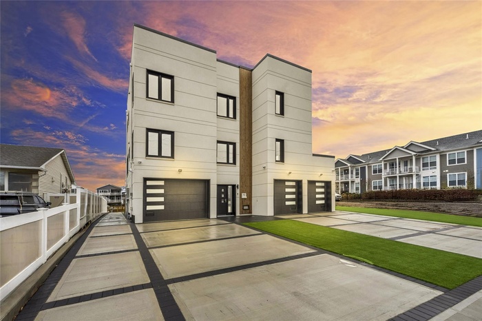 View of front of home featuring a garage, driveway, and stucco siding