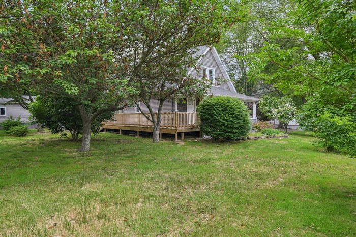 View of green lawn featuring a wooden deck