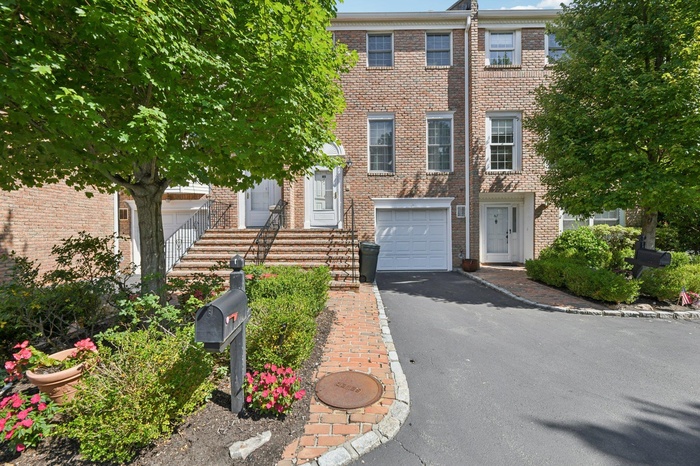 View of front of home with a garage, asphalt driveway, and brick siding