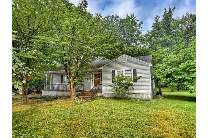 View of front of house with a front lawn, covered porch, and roof with shingles