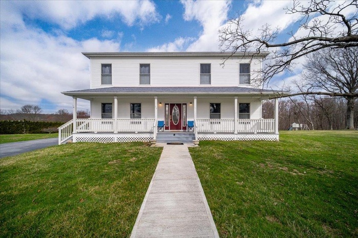 Country-style home with a front yard and a porch