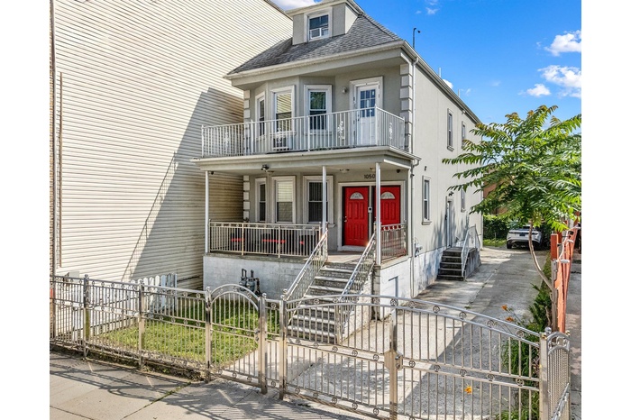 View of front facade featuring a porch, roof with shingles, a fenced front yard, a gate, and stairs