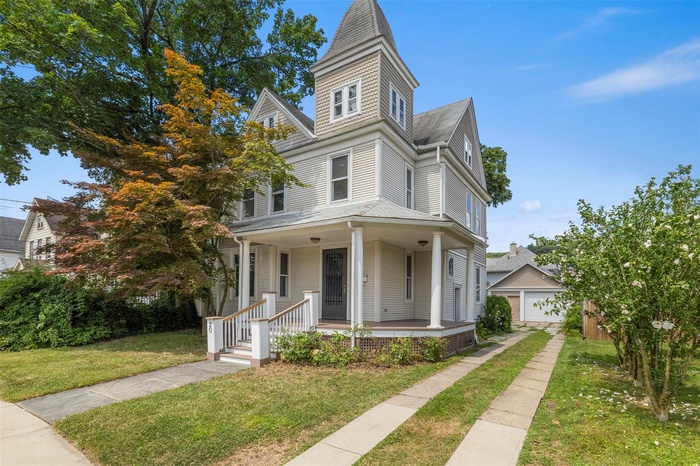 View of front of home featuring a porch, a front lawn, and a garage