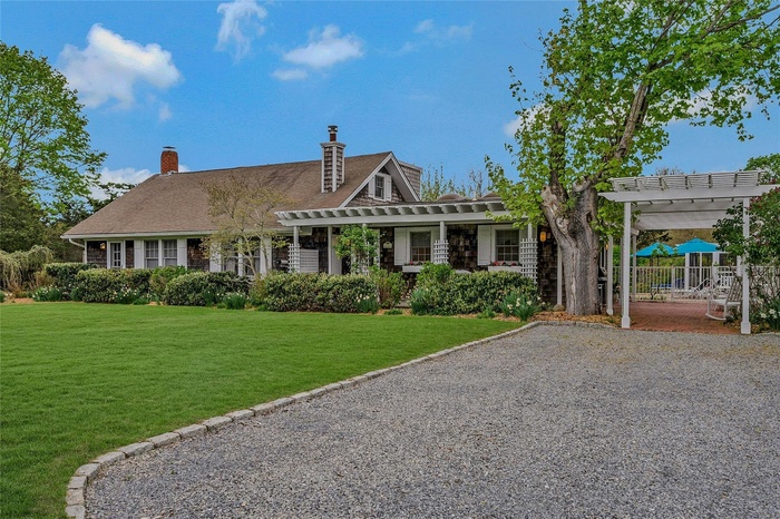 Shingle-style home featuring a pergola, a front yard, and a chimney