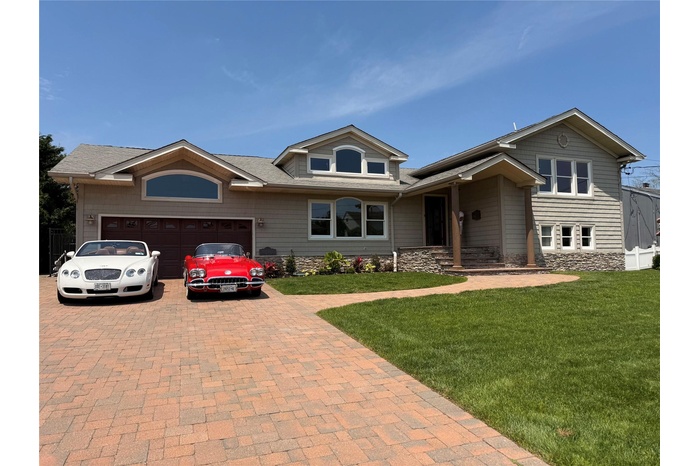 View of front of home featuring decorative driveway, an attached garage, a front lawn, and a shingled roof