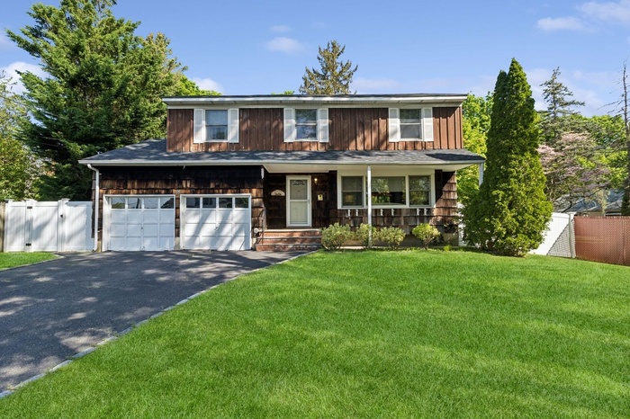 View of front of house with driveway, a gate, a porch, and board and batten siding