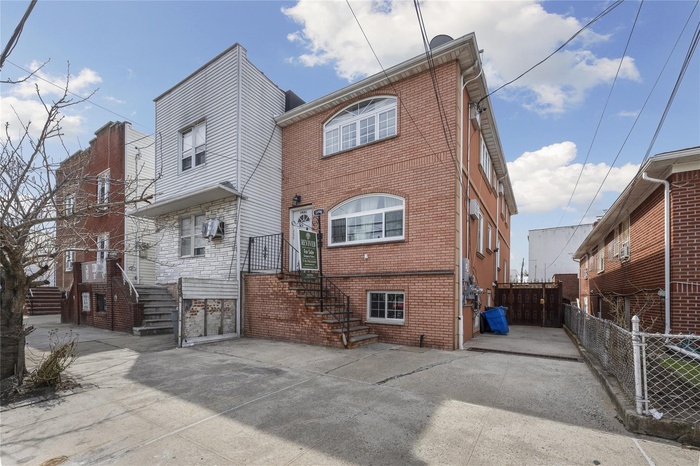Back of property with driveway, fence, and brick siding