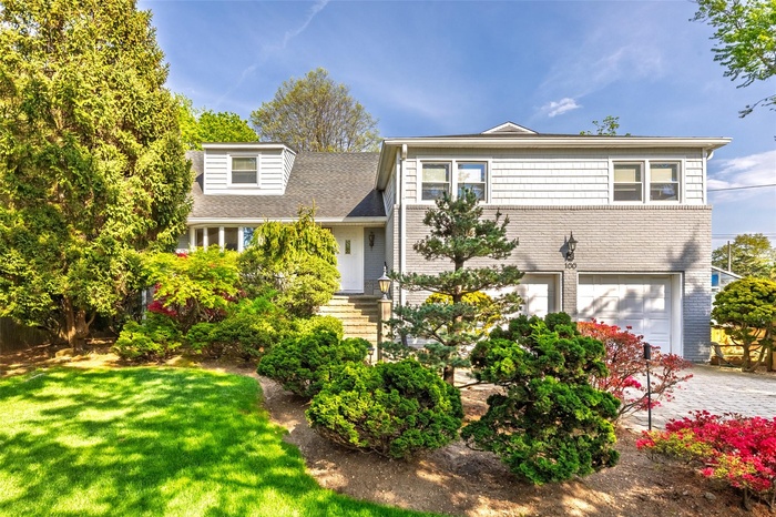 View of front of property featuring an attached garage, driveway, and a front yard