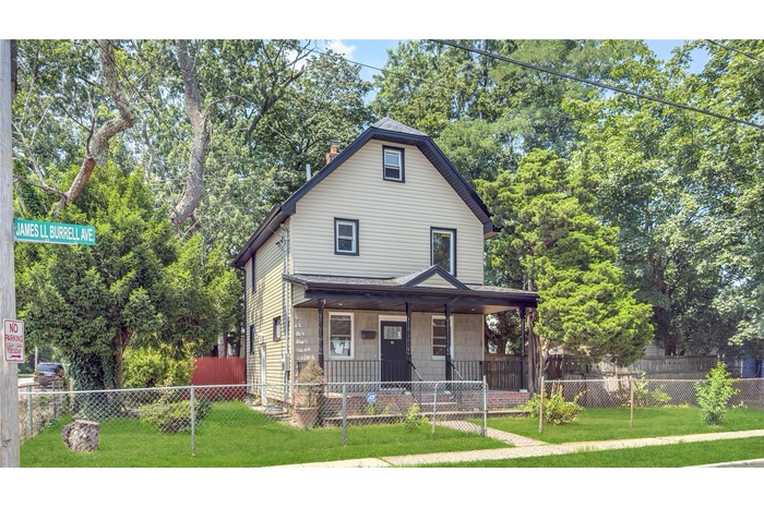 View of front facade featuring a porch, a chimney, and a fenced front yard