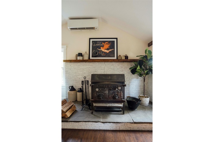 Detailed view of wood finished floors, a wall mounted air conditioner, and a wood stove