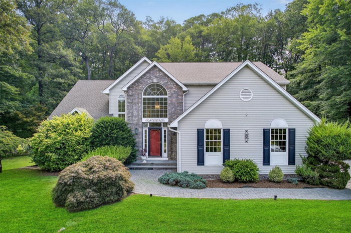Traditional home with a front yard, a shingled roof, and brick siding