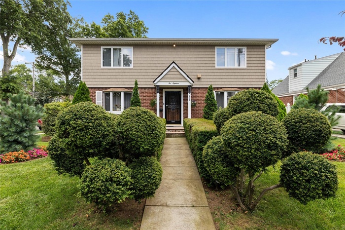 Colonial home with brick siding and a front lawn