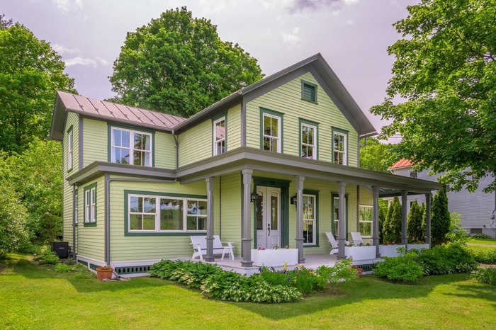 View of front of home featuring covered porch, a standing seam roof, a front yard, and a metal roof