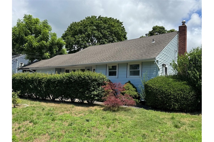 View of front of home featuring roof with shingles, a chimney, and a front lawn