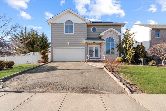 Traditional-style house with french doors, asphalt driveway, brick siding, an attached garage, and solar panels