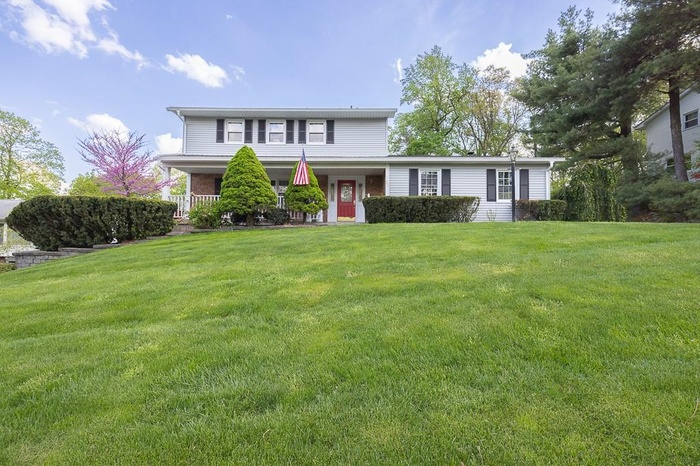 Colonial-style home featuring a porch and a front yard