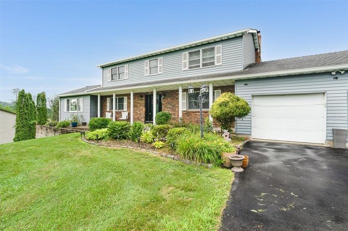 Traditional-style house with a 2 car garage, driveway, porch, and landscaped front yard
