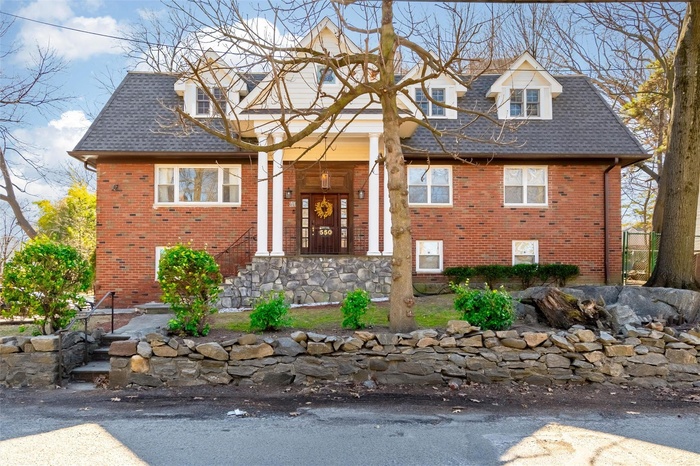 View of front facade with brick siding and a shingled roof