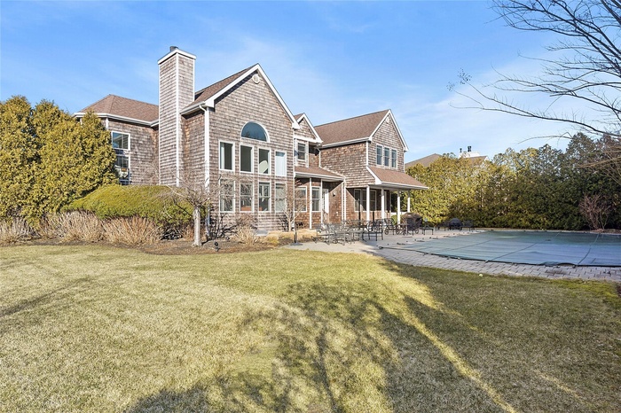 Back of house featuring a yard, a patio, and a chimney