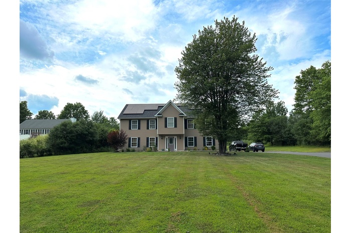 View of front of house featuring solar panels and a front yard