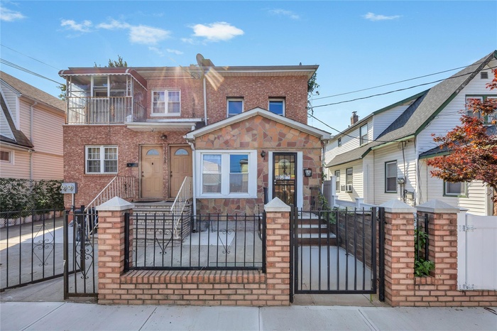 View of front facade featuring a fenced front yard, a gate, and brick siding