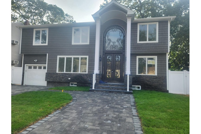 View of exterior entry with french doors, an attached garage, decorative driveway, and stone siding