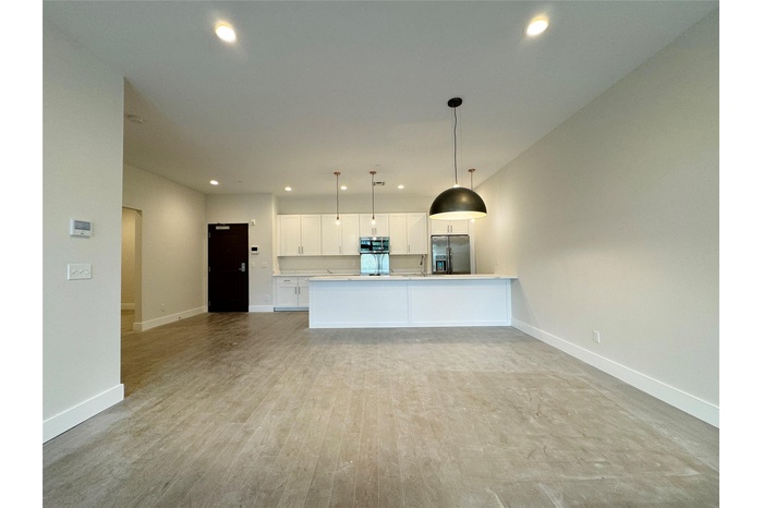 Kitchen featuring stainless steel appliances, open floor plan, white cabinetry, recessed lighting, and decorative light fixtures