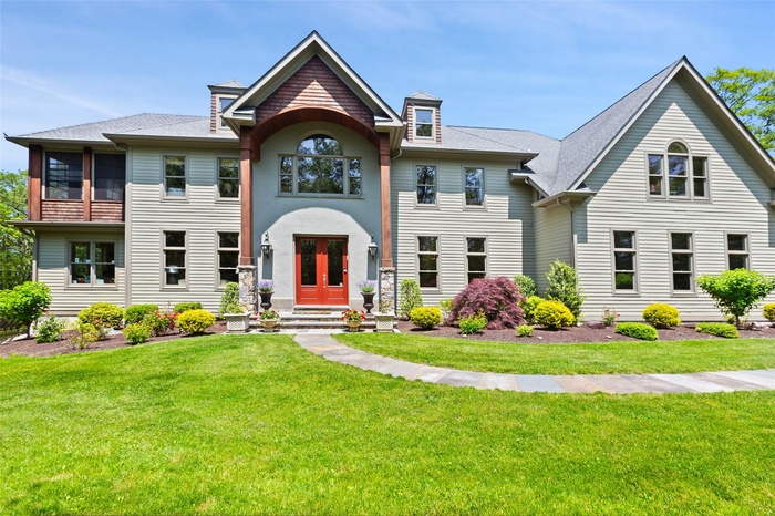 View of front facade featuring a front yard, a shingled roof, and french doors